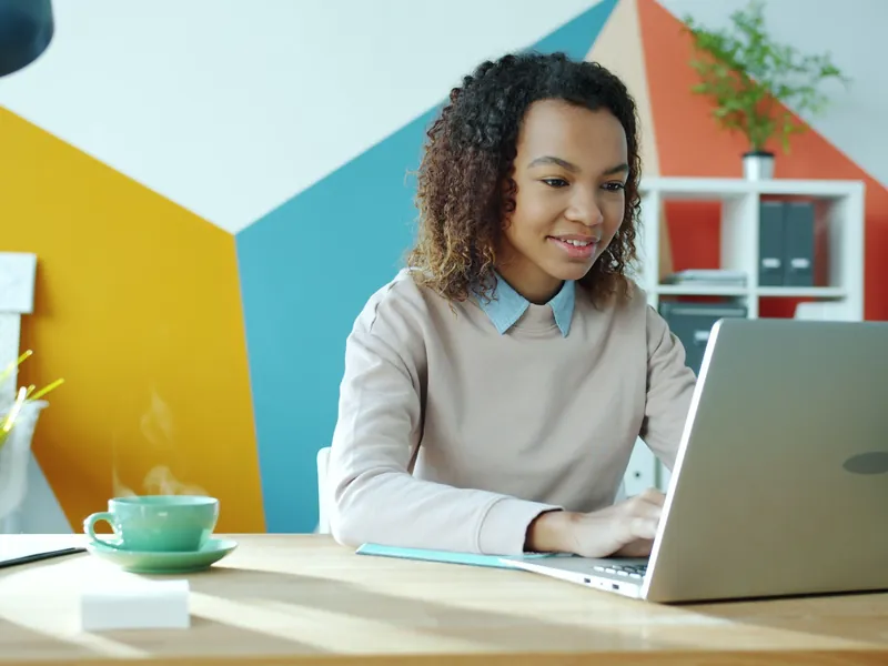 Jeune femme concentrée sur son ordinateur portable dans un bureau lumineux et coloré