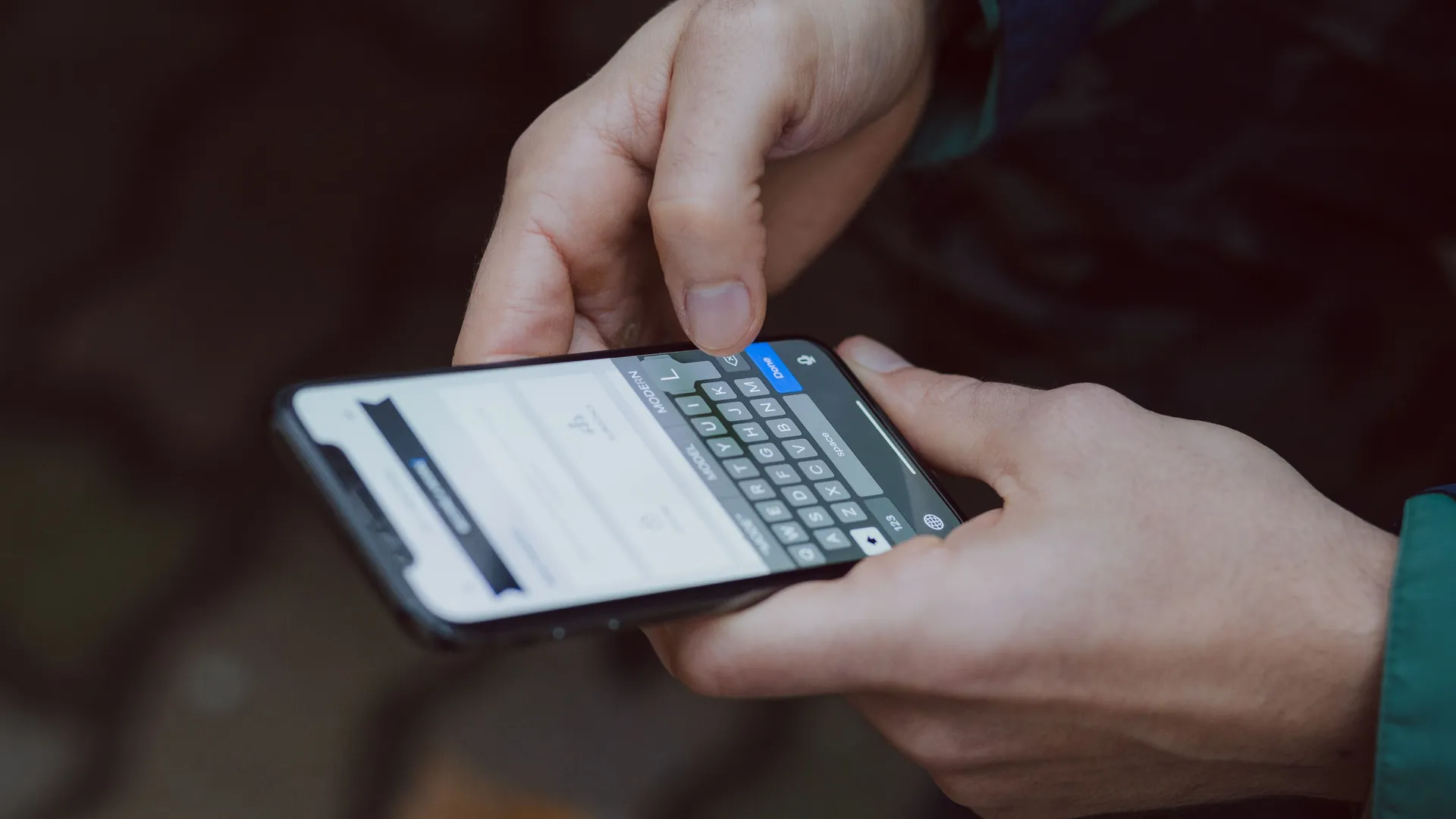 Gros plan de mains tenant un téléphone et écrivant un message