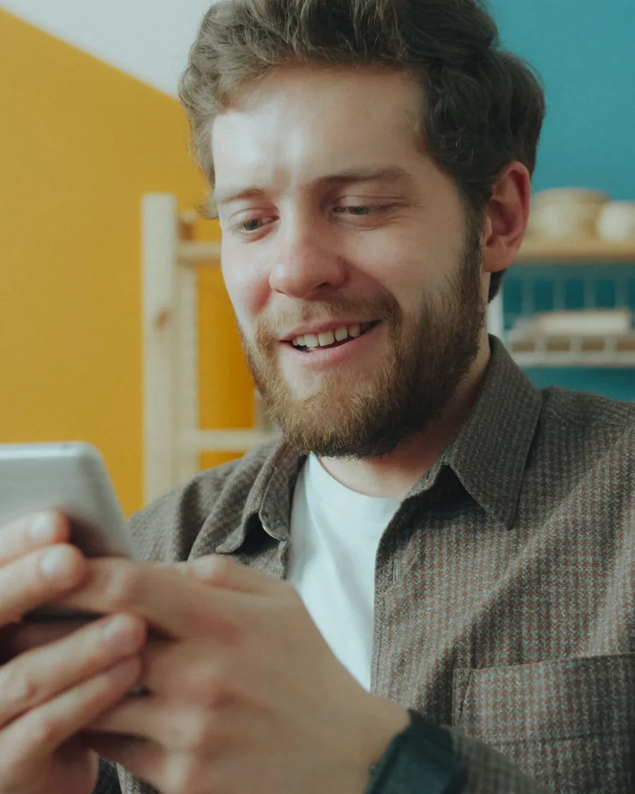 Homme souriant qui saisit des informations sur son téléphone